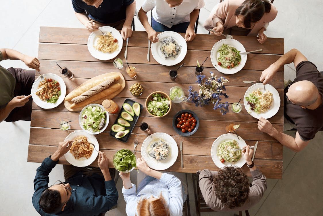 A family sharing supper around a wooden table, seen from above.